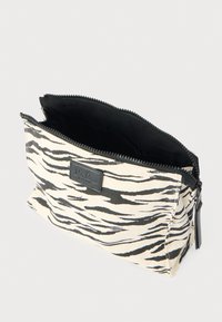 Φάκελος με φερμουάρ σε μπεζ χρώμα με μαύρες ρίγες τίγρης, κατασκευασμένος από καμβά. Διαθέτει μαύρη επένδυση και μια μικρή δερμάτινη ετικέτα με λογότυπο στην πρόσοψη.