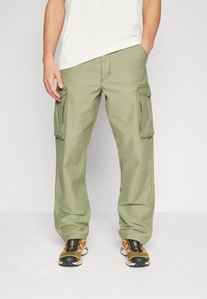 Green cargo pants with a relaxed fit, featuring large side pockets, stitched detailing, and durable fabric. Paired with black and orange sneakers.
