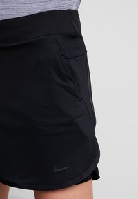 Černé sportovní šortky s texturovanou látkou, elastickým pasem a bočními kapsami. Na lemu je malé šedé logo Nike.