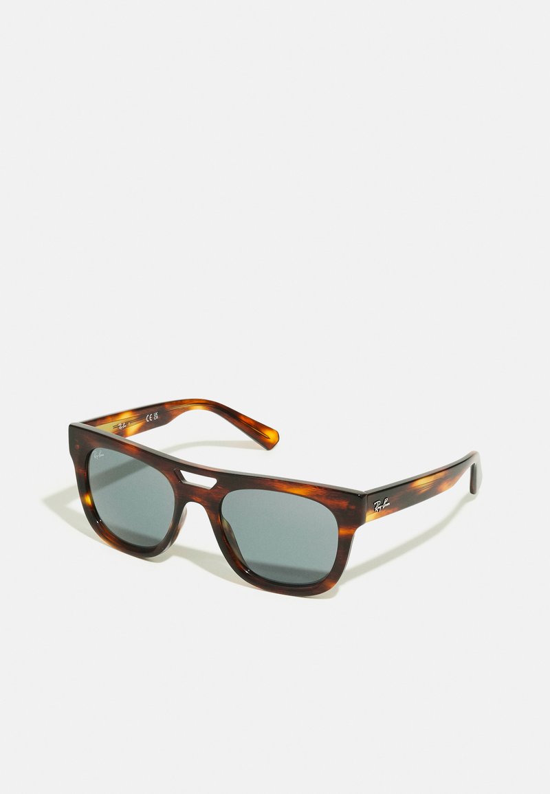 Óculos de sol em padrão tartaruga com lentes escuras, de forma retangular e com design de ponte em forma de chave. Apresenta a marca Ray-Ban na lateral.