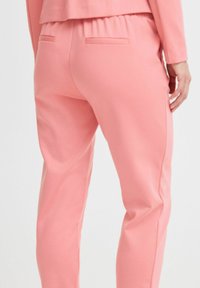 Rosa Stretch-Stoff-Hosen mit lockerer Passform, ausgestattet mit einem elastischen Bund, Gesäßtaschen und einer glatten Textur.