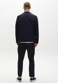 Navy jacket and trousers made of smooth fabric, featuring a simple design and clean lines, with minimalistic accents and a modern fit.