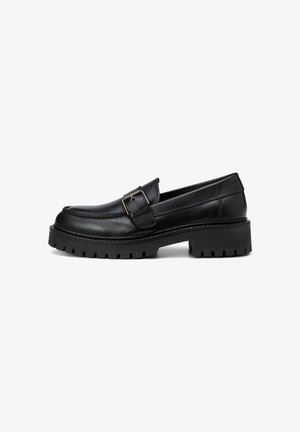 Schwarze Leder-Loafer mit einer groben Profilsohle, die einen Schnallenakzent am Riemen und gestochene Details entlang des Obermaterials aufweisen.
