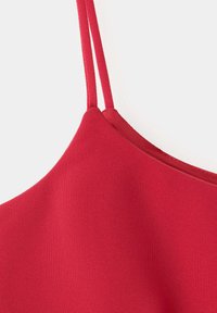 Gros plan sur un vêtement en tissu rouge avec de fines bretelles doubles et une surface à texture lisse.