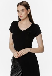 Czarny t-shirt z dekoltem w serek, wykonany z miękkiej bawełny, z krótkimi rękawami, posiadający małe okrągłe logo na lewej piersi, dopasowany krój.