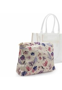 Pochette à motif floral dans des tons roses et violets sur un fond clair, fabriquée en matière douce avec une fermeture éclair dorée. Tote transparent en arrière-plan.