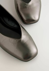 Bailarinas grises metálicas con punta afilada y textura suave, que presentan un diseño elegante y un tacón bajo.
