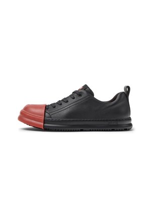 Black sneaker with a red rubber toe cap, leather upper, lace-up design, padded collar, and a textured sole. Features a rear pull tab.
