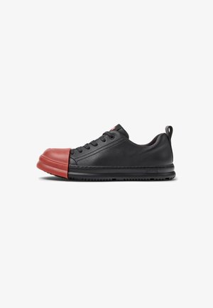 Sneaker nera con punta in gomma rossa, tomaia in pelle, design con lacci, collo imbottito e suola testurizzata. Presenta un tassello sul retro per facilitare la calzata.