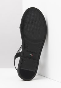 Sandalo nero con suola in gomma testurizzata, cinturino regolabile e design minimalista. Presenta un marchio e l'etichetta "fatto in Italia". Taglia 37.