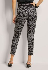 Schwarz-graue, taillierte Hosen mit Leopardenmuster, aus glattem Material und elastischem Bund, endend knapp über dem Knöchel.