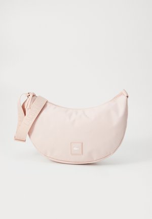 Hellrosa, mondförmige Tasche mit verstellbarem Trageriemen und Lacoste Paris-Logo-Patch auf der Vorderseite.