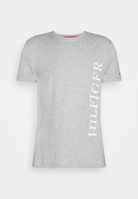Grå bomulds t-shirt med klassisk rund halsudskæring. Har hvid "HILFIGER" tekst lodret langs venstre side. Korte ærmer.