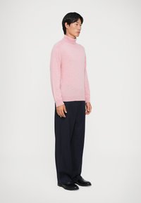 Lichtroze coltrui met geribde kraag en manchetten, gecombineerd met donker marineblauwe pantalon met streepdessin. Glad textuur, casual pasvorm.