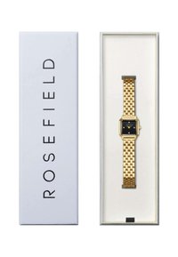 Reloj de metal dorado con esfera negra cuadrada, pulsera de eslabones y pequeños adornos. Presentado en una caja blanca con la impresión "ROSEFIELD".