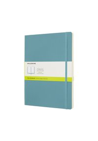 Quaderno con copertina morbida di colore blu, con pagine bianche lisce. Presenta un'etichetta verde e bianca, chiusura con elastico e angoli arrotondati.