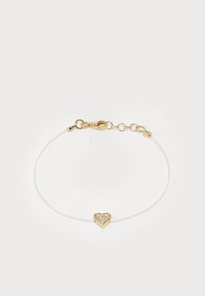 Bracelet featuring a white, thin cord with a gold heart-shaped charm adorned with sparkling stones and a clasp closure.