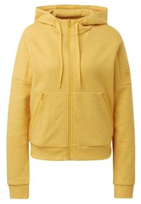 Žlutá mikina na zip s měkkým, texturovaným materiálem, předními kapsami a kapucí se stahovací šňůrkou. Na rameni je logo Adidas.