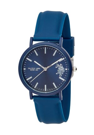 Montre-bracelet ronde bleue avec index argentés, trois aiguilles, un bracelet en silicone bleu, et logo U.S. Polo Assn. sur le cadran.