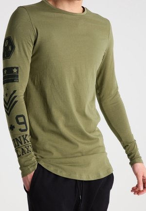 Olivenfarbene Langarm-T-Shirt mit Rundhalsausschnitt, versehen mit schwarzen Druckgrafiken und Text auf dem linken Ärmel und der Vorderseite. Weiche Stoffstruktur.