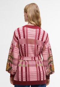 Πλεκτό cardigan με ροζ και κόκκινο καρό σχέδιο, κεντητά λουλούδια στα μανίκια και σχέδιο με ζώνη στη μέση.