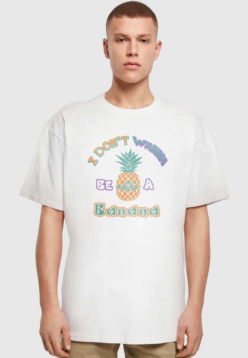 Hvit bomulls T-skjorte med et fargerikt grafisk trykk av en ananas og teksten "JEG VIL IKKE VÆRE EN BANAN" i lekne fonter.