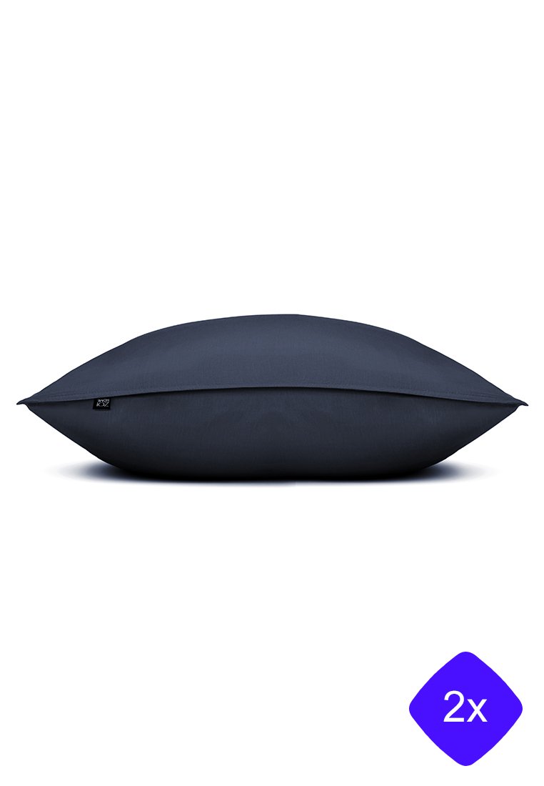 Cuscino rettangolare blu scuro con tessuto liscio, forma leggermente bombata e una piccola etichetta logo su un lato. Texture morbida, design minimale.