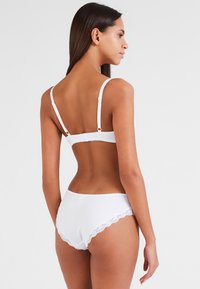 Witte lingerieset met een naadloze bralette met verstelbare bandjes en bijpassende hoge taille slips met kantdetail.