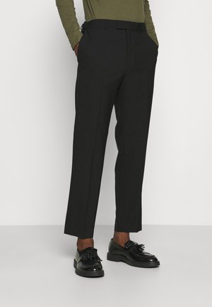 Pantaloni neri su misura con vestibilità slim, dotati di passanti per cintura, tasche laterali e piega frontale, abbinati a mocassini neri.