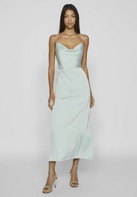 Satin midi-klänning i ljus mintgrön, med tunna axelband, en söt hjärtformad halsringning och subtil drapering längs midjan. Guldiga remsandaler.