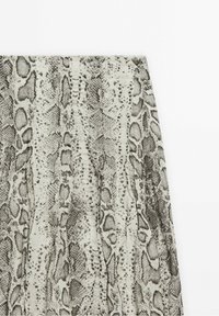 Jupe taille haute avec imprimé peau de serpent dans des tons de gris et noir sur fond beige.