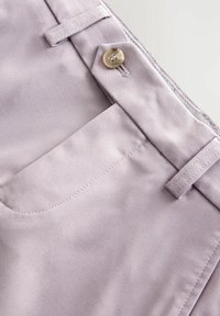 Pantalons lavande clair avec une texture lisse, dotés d'une fermeture à bouton, de poches avant et de détails de couture précis.
