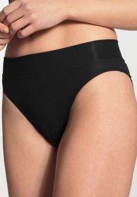 Bikini en coton noir avec une large ceinture et une texture lisse. Présente un design minimaliste avec une ouverture de jambe haute.