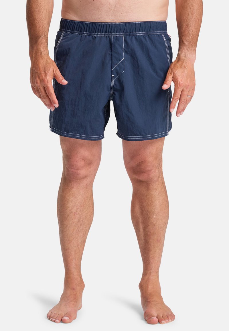 Navy blue swim shorts with elastic waistband, three-panel design, white stitching detail, and no pockets. Made from lightweight material.