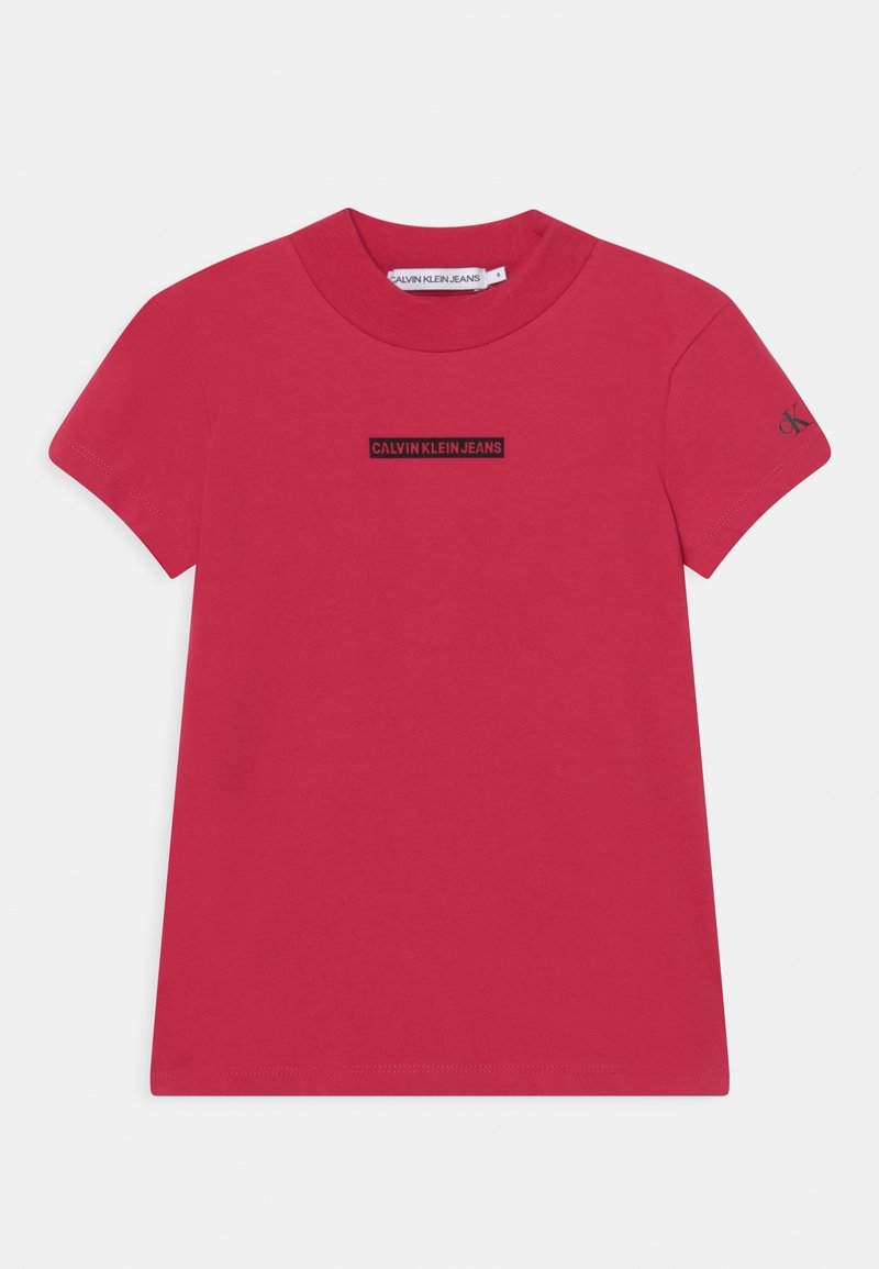 Camiseta de algodón roja con mangas cortas, cuello redondo, que presenta un logotipo rectangular negro "CALVIN KLEIN JEANS" en el pecho. Textura suave.