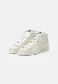 High-top sneakers in off-white leather with textured accents, flat laces, round toe, and a distressed rubber sole. Brand logo on tongue.