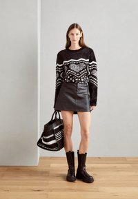 Maglione a righe bianco e nero, mini gonna in pelle nera, alti stivali neri con plateau e una borsa a righe con manici.