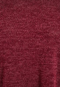 Burgundowa dzianina z teksturowanym wzorem. Powierzchnia ukazuje różne detale ściegów, tworząc lekko nierówny wygląd.