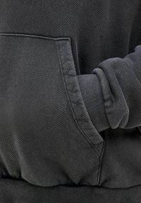 Gray sweatshirt featuring a front pocket, ribbed cuffs, and a textured fabric. The hem is also ribbed, providing a layered look.