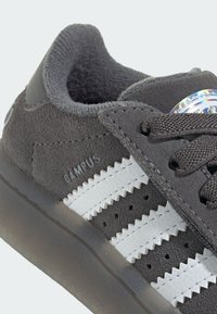 Gray suede sneaker with white leather stripes, textured laces, and a translucent rubber sole. “CAMPUS” logo on the side.