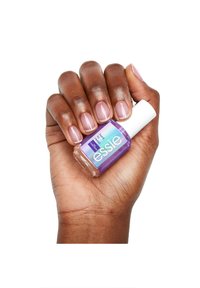 Bouteille de vernis à ongles violet avec un capuchon blanc, tenue dans une main avec des ongles naturels peints d'une teinte rose clair. Le texte indique "essie hard to resist."