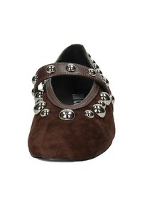 Scarpa in suede marrone con punta arrotondata, caratterizzata da una fascia in pelle marrone decorata con borchie d'acciaio argentato attorno all'apertura.