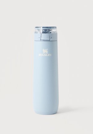 Bouteille de voyage isolante Stanley en acier inoxydable bleu clair avec bouchon rabattable transparent sur fond blanc.
