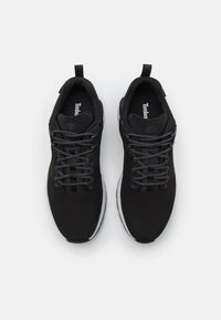 Mustat urheilukengät, joissa on sileä ylempi osa, teksturoidut nauhat ja pehmustettu pohja. Sisältää logon kielekkeellä ja vetonauhan kantapäässä.