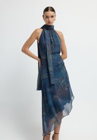 Vestido asimétrico tipo halter en azul, con un diseño de paisley. Confeccionado con tela ligera, cuenta con un detalle drapeado y una superposición transparente.