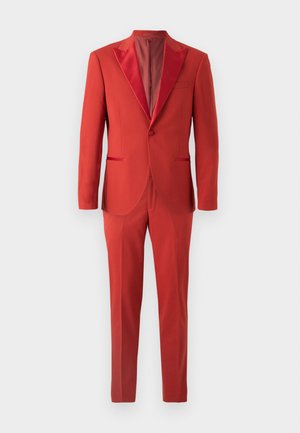 Traje rojo de corte ajustado. Chaqueta de un botón con solapa de satén, combinada con pantalones a medida. Textura de tejido suave en todo el conjunto.