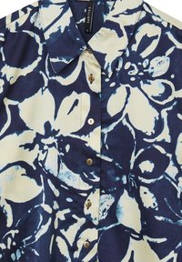 Chemise bleu marine et beige à motifs floraux, à col pointu et petits boutons en bois, taille S.