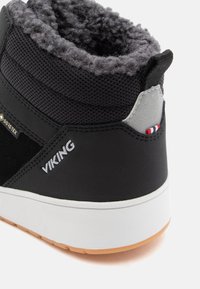 Bota de inverno preta com forro de lã cinza, logótipo branco "VIKING", etiqueta Gore-Tex e sola branca com padrão castanho claro.