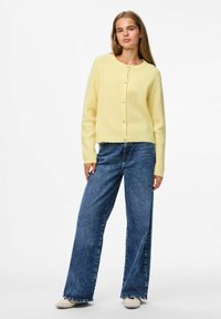 Dzeltena ribota kardigāna ar apaļu dekoltē, pogu aizdari un garām piedurknēm, kombinēta ar augsto vidukļa zilo platā kāju džinsiem.