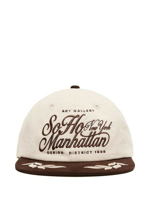 Casquette de baseball blanche et marron avec ""SoHo Manhattan New York"" brodé à l'avant et surpiqûres décoratives sur la visière marron.